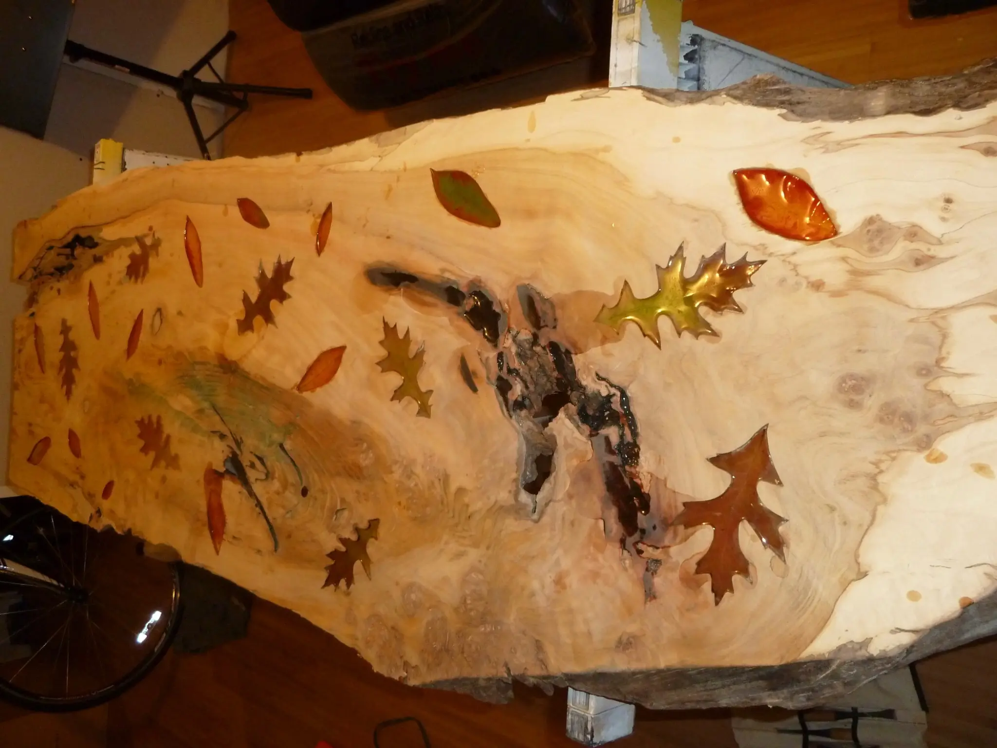 Autumn leaves being carved and fitted into the live-edge slab